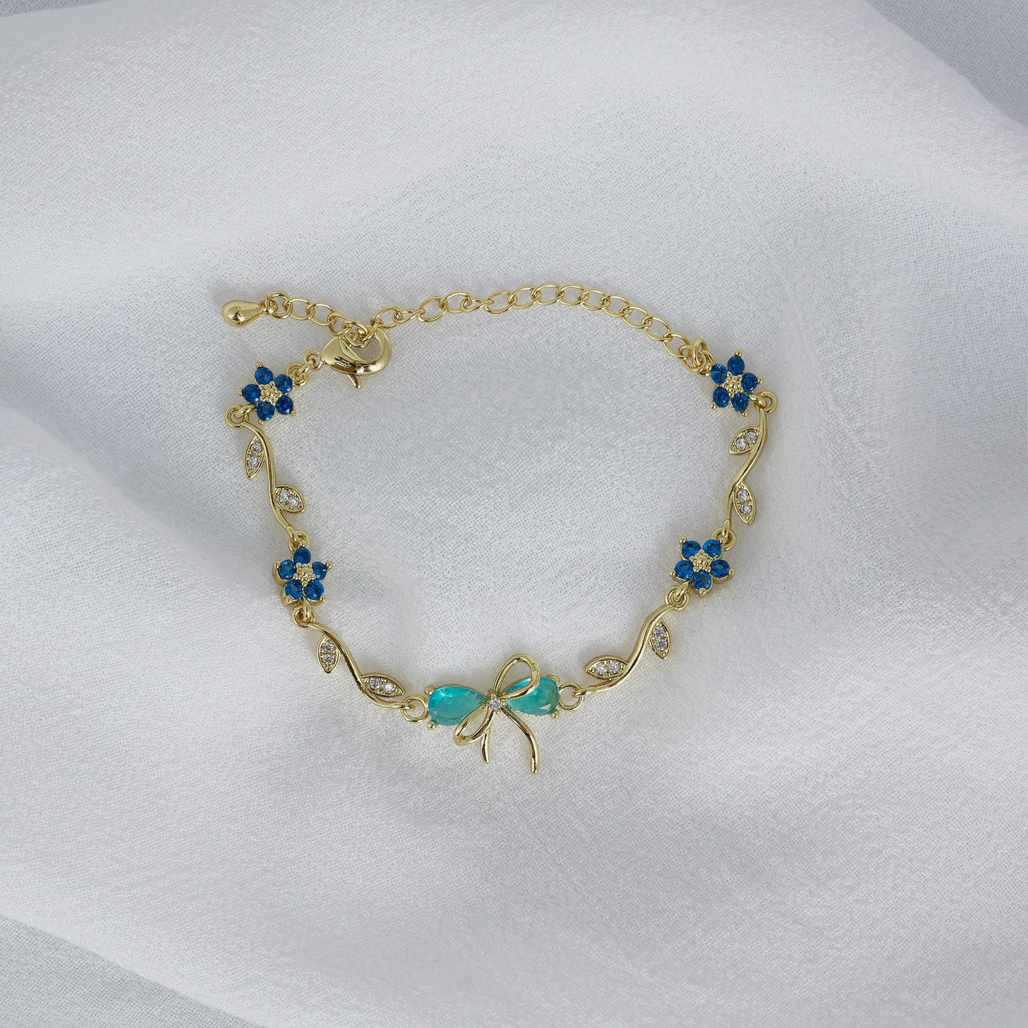 Gold bracelet with blue bow on a white background