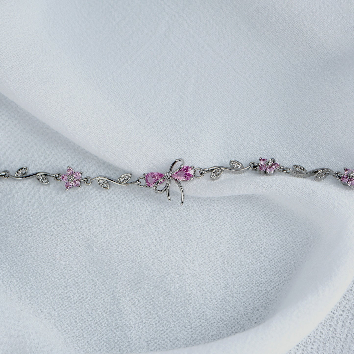 Silver Bow bracelet with pink gemstones on a white background