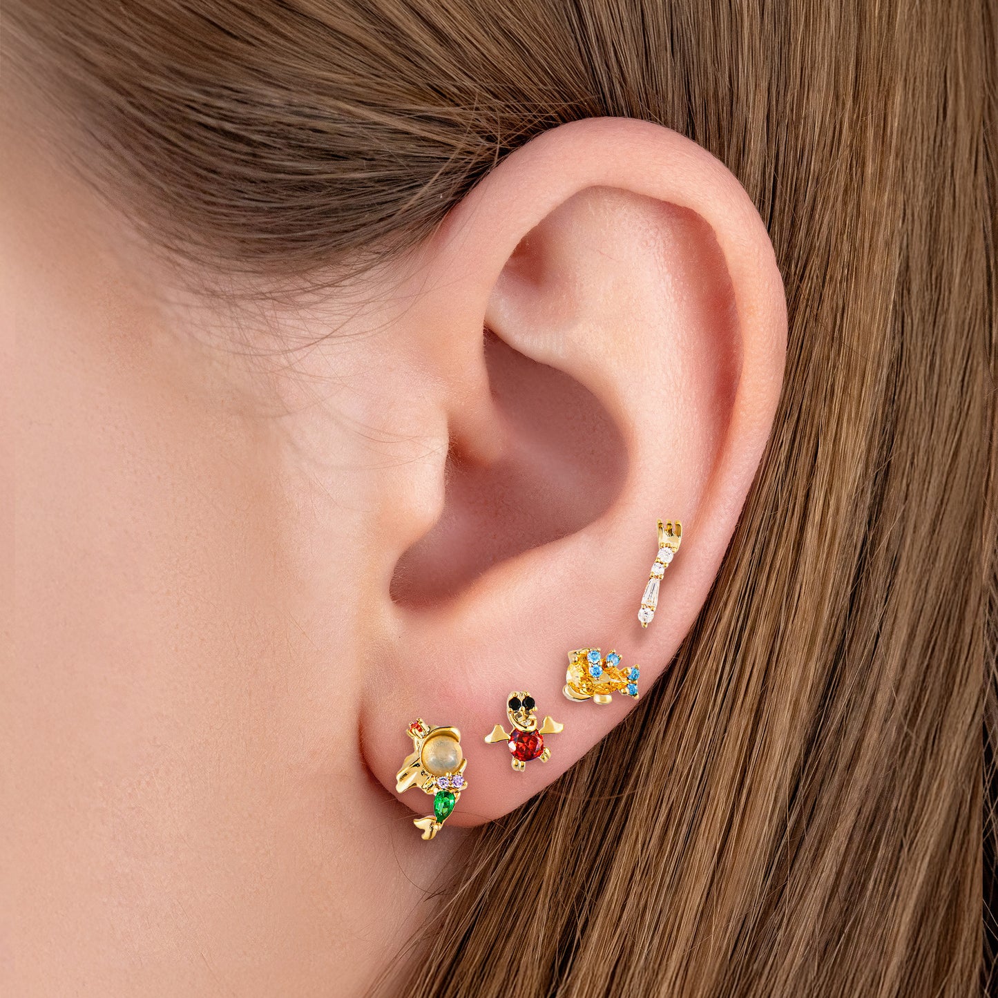 Close-up of an ear wearing The Little Mermaid gold earrings.