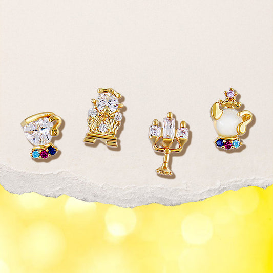Set of gold Enchanted Objects earrings with gemstones on a light yellow background
