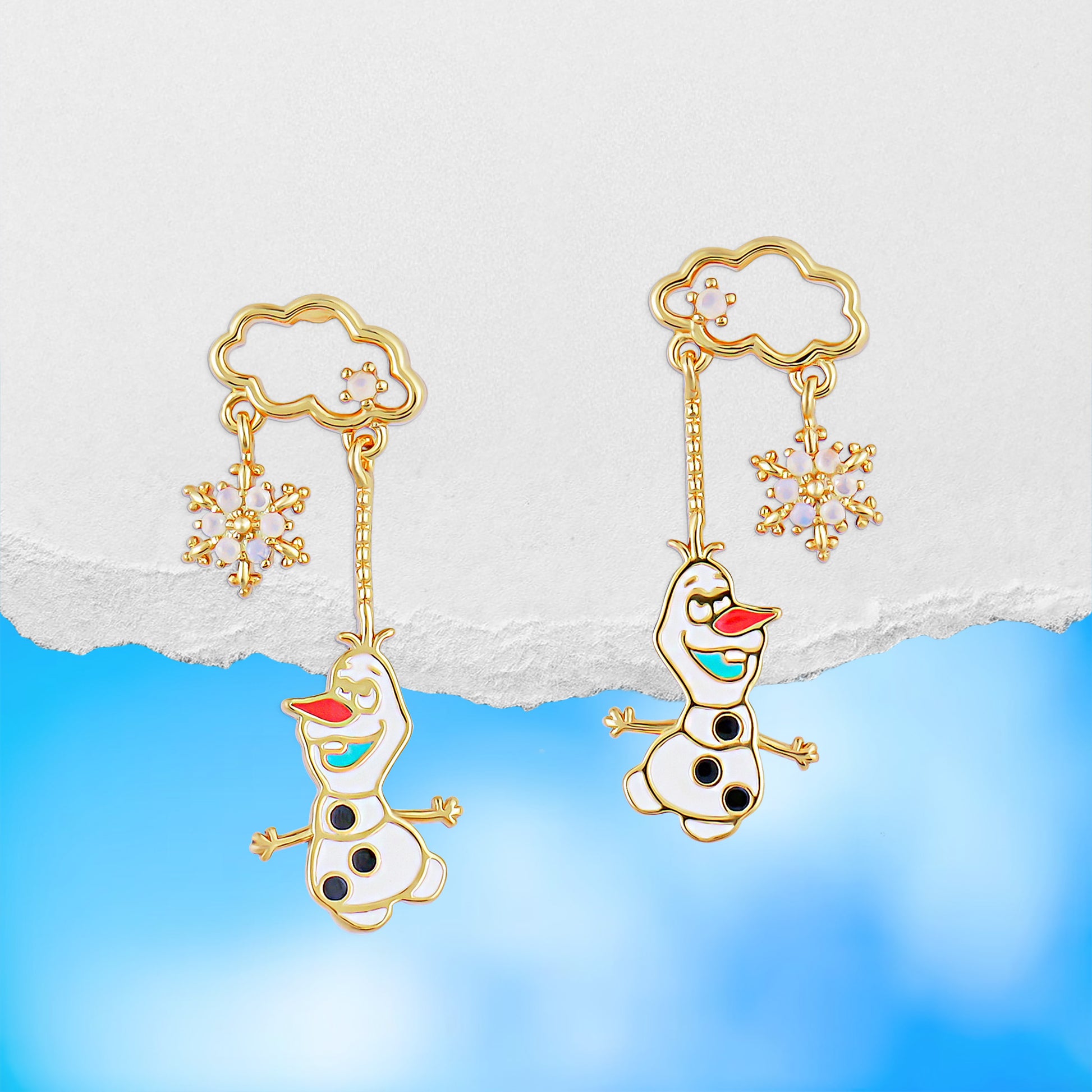 Gold Olaf dangle earrings with snowflakes on a light blue background