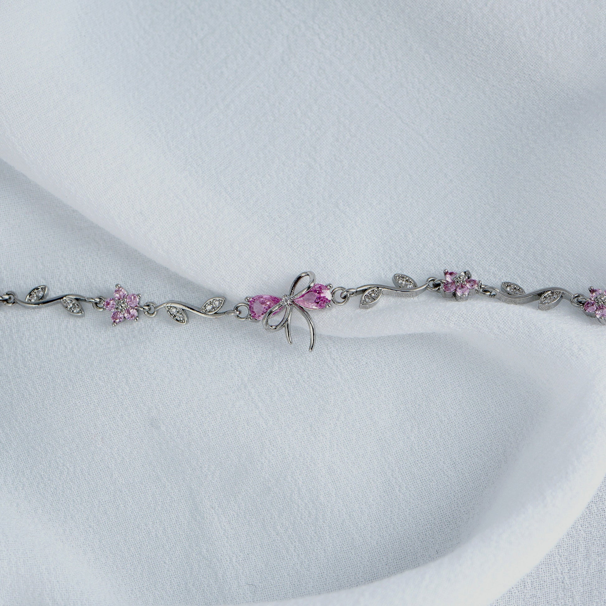 Silver Bow bracelet with pink gemstones on a white background