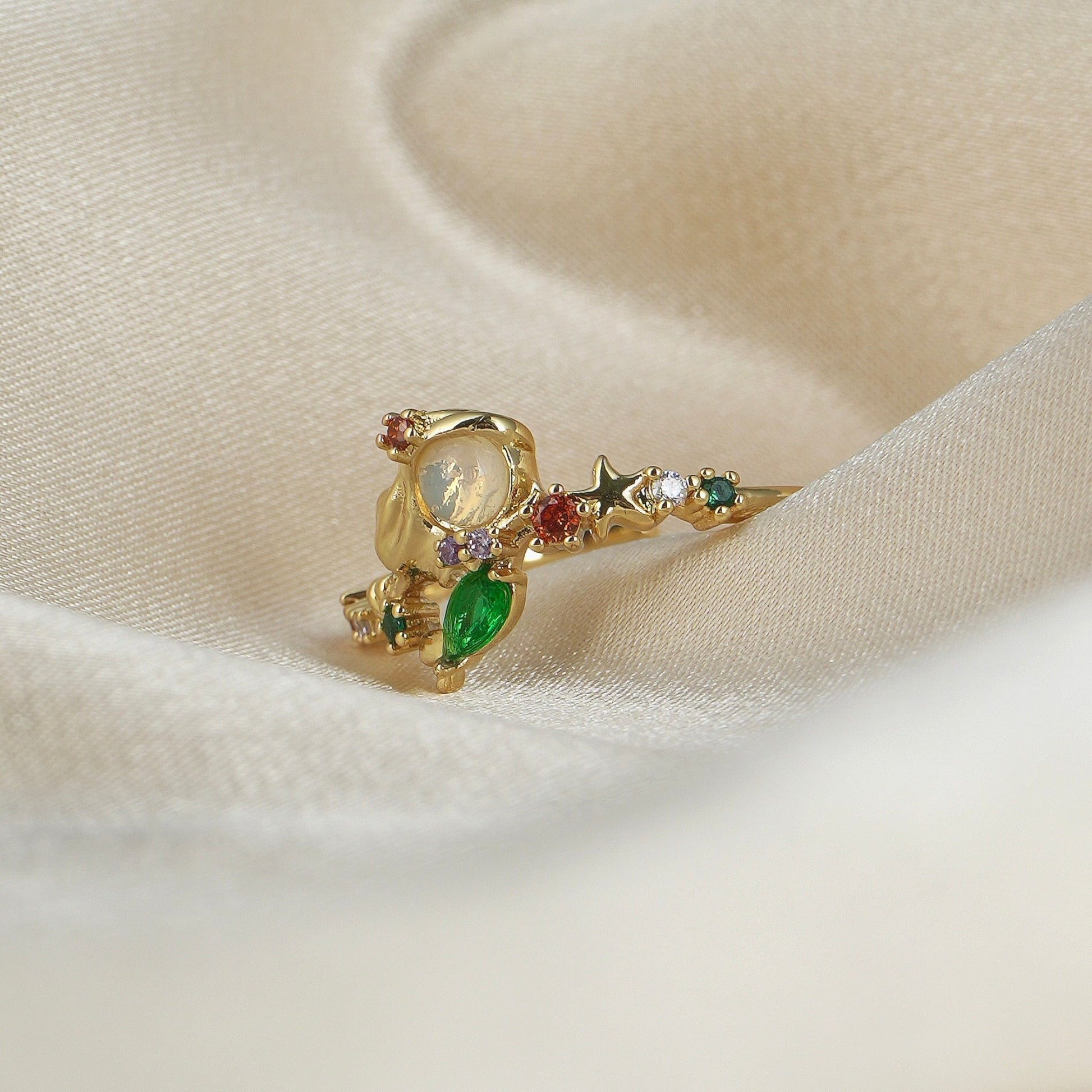 Princess Ariel ring with colorful gemstones on a beige fabric background