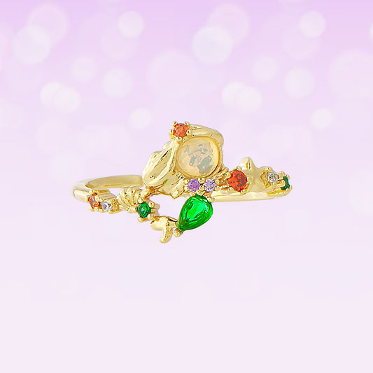 Princess Ariel gold ring with colorful gemstones on a light purple background