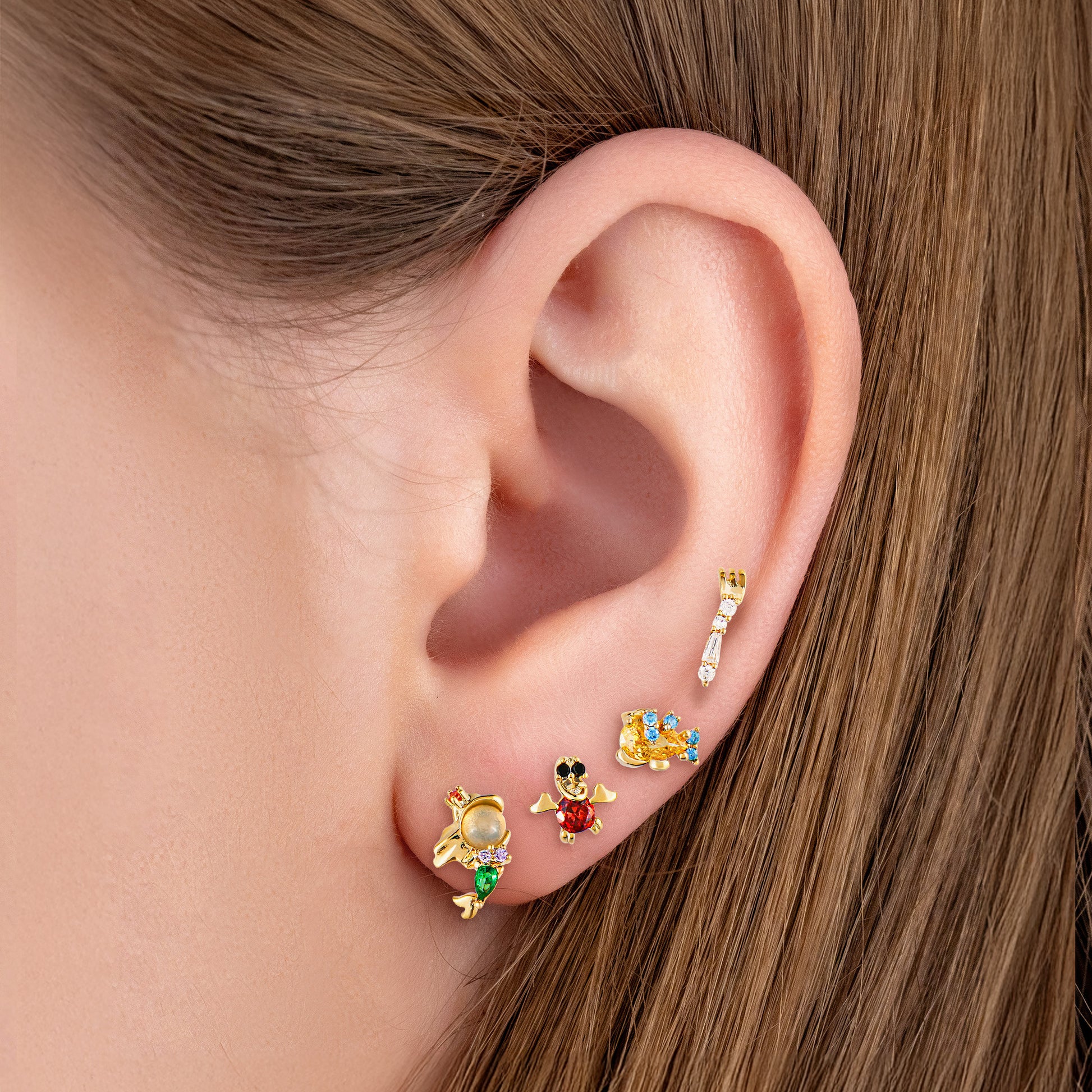 Close-up of an ear wearing The Little Mermaid  gold earrings.