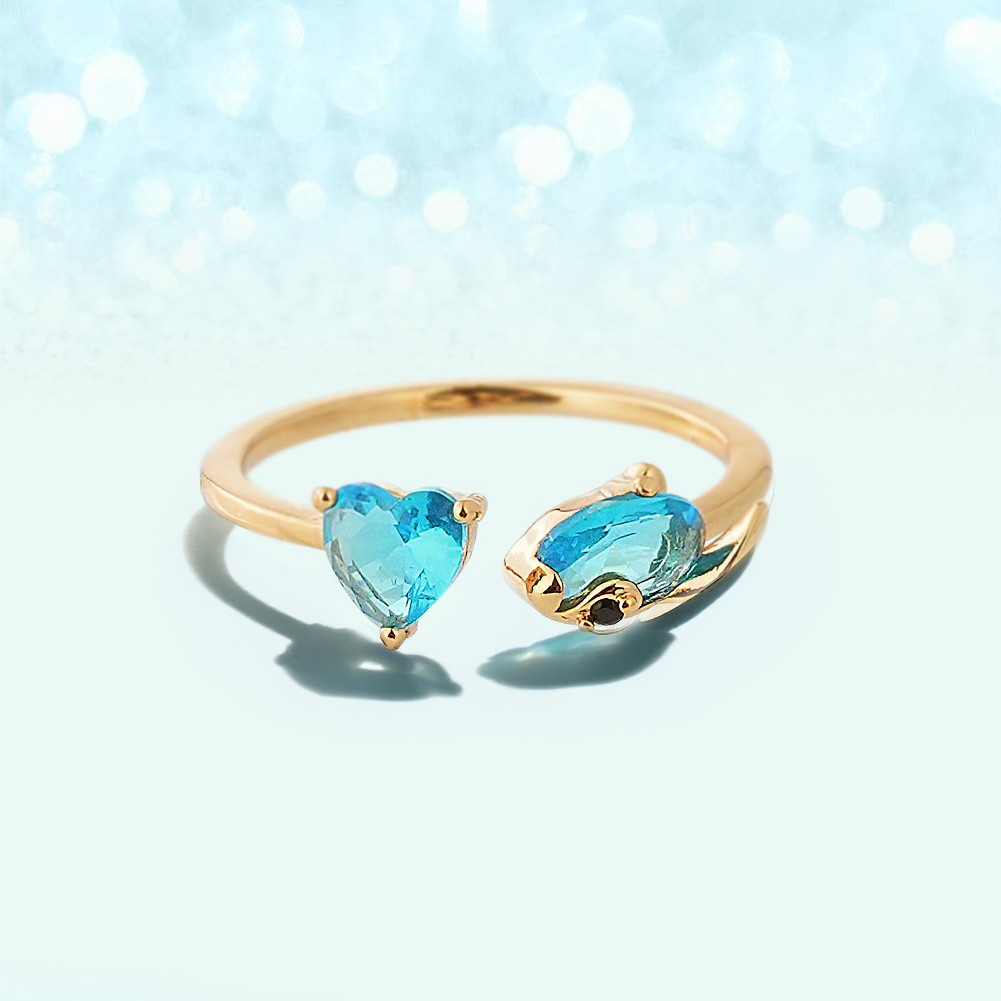 Unit 626 Stitch gold ring with heart-shaped blue gemstones on a light blue background